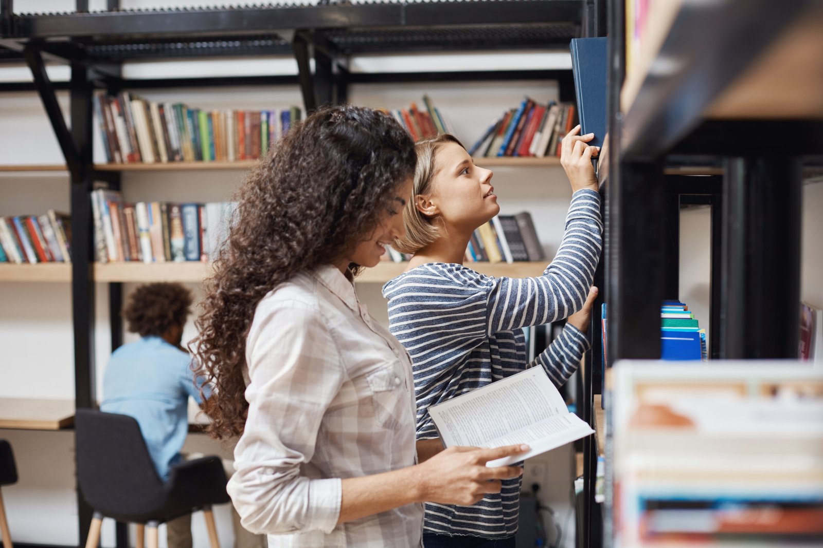 two-young-cheerful-female-students-casual-clothes-standing-near-bookshelves-university-library-looki.jpeg